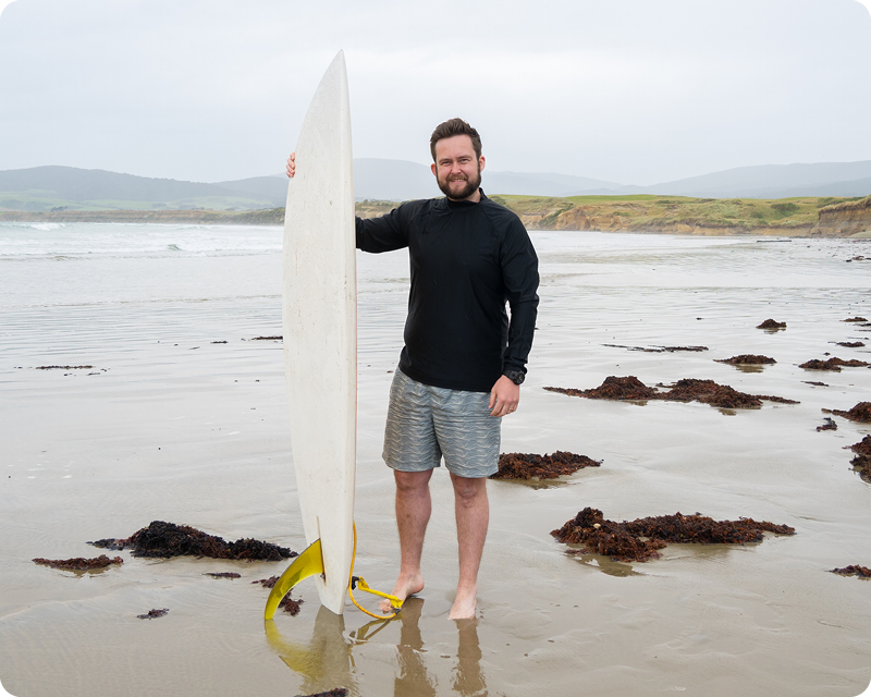 Man with surfboard at Monkey Island, Orepuki