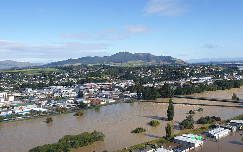 Aerial view of the Mataura River in flood at Gore township. The image shows the stop banks to the north and south of the State Highway 1 road and rail bridges at capacity with the floodwaters. There is flooding on the true left of the river. 