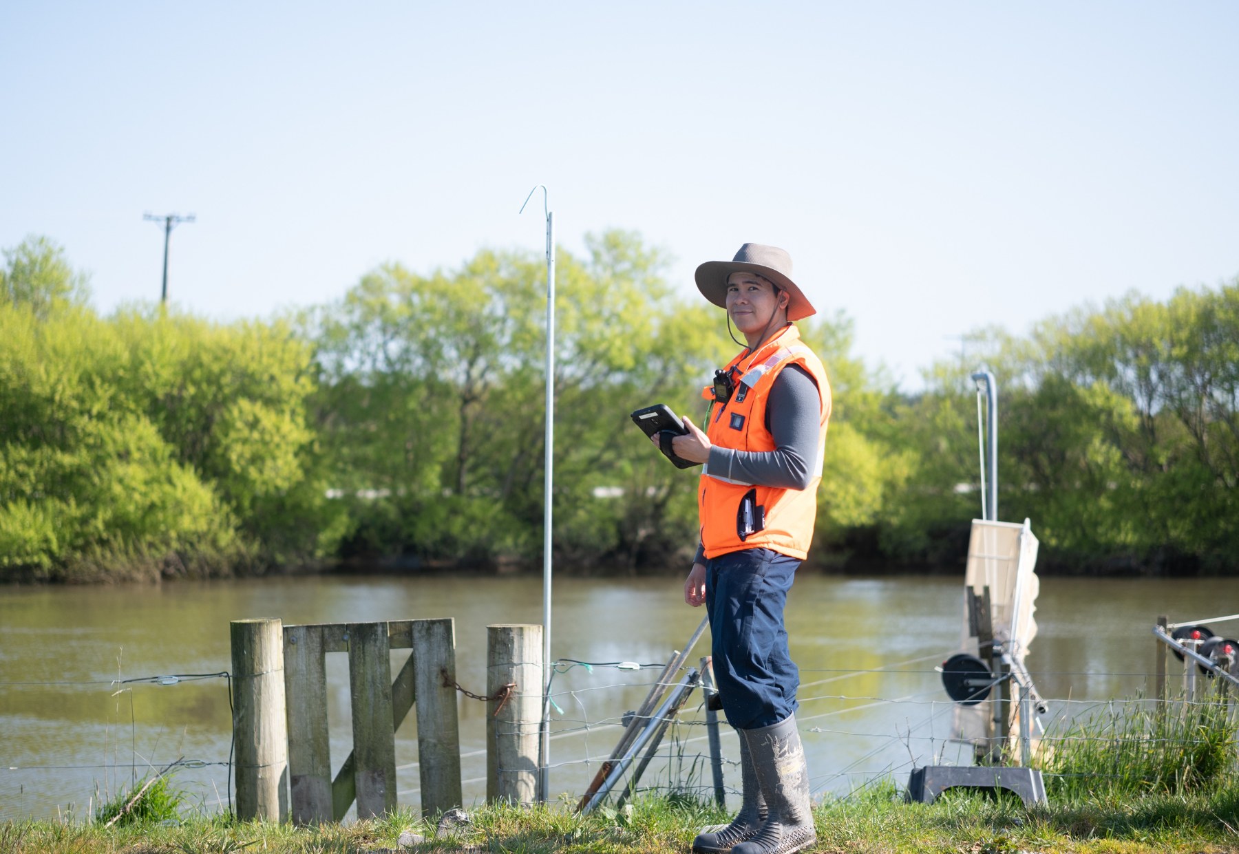 ​Environment Southland compliance officer Lance Daleon standing next to a river with monitoring equipment.